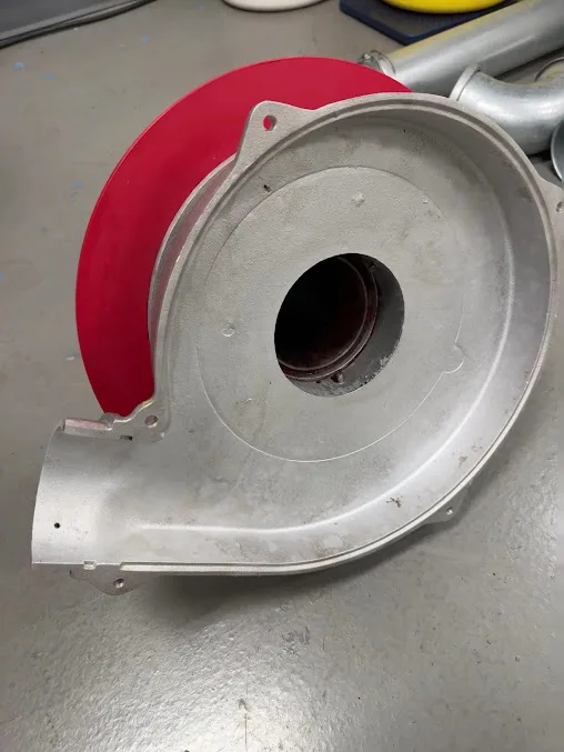 A blower housing after dry ice blasting, bare aluminum with a red gasket edge