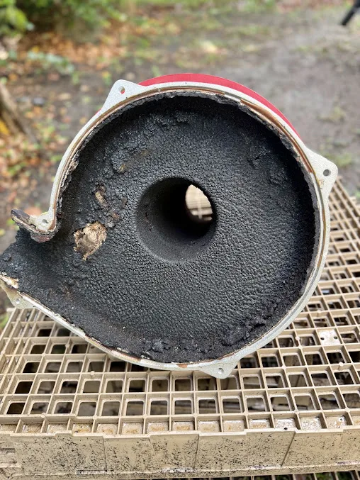 A blower housing before cleaning, caked in black carbon