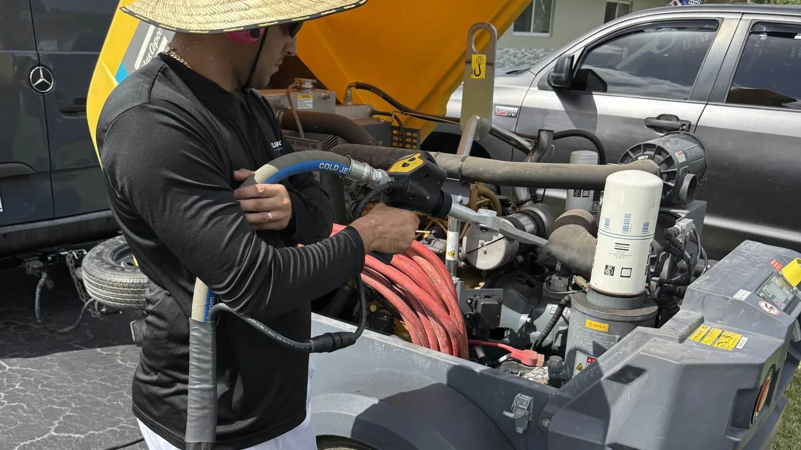 Giancarlo working the dry ice nozzle into the hydraulics and filter housing of a yellow dump trailer