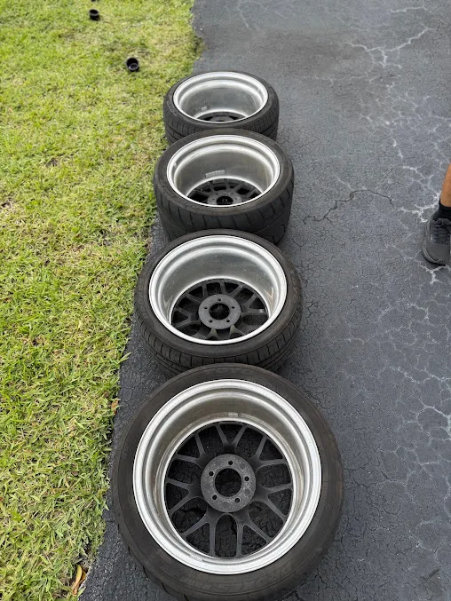 Four refinished alloy wheels lined up on the grass after cleaning
