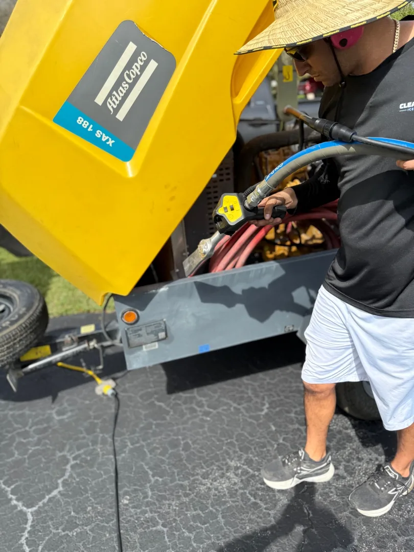 Blasting under the raised yellow hood of an Atlas Copco towable compressor