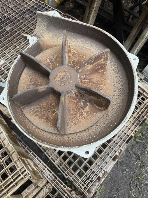 A squirrel-cage fan wheel heavy with deposit before cleaning